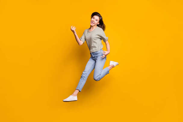 Full size photo of young beautiful funky happy smiling girl jump play invisible guitar isolated on yellow color background. - Fotó, kép