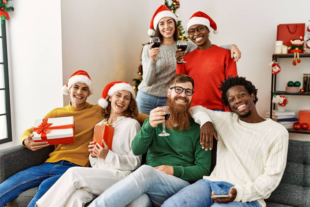 Group of young people on christmas celebration sitting on the sofa at home. - Foto, afbeelding
