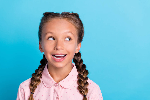 Photo of young cheerful little girl happy positive smile look empty space curious isolated over blue color background. - Foto, afbeelding