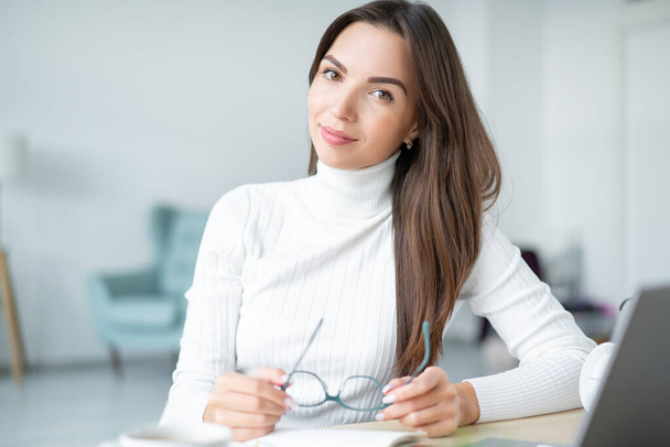 Portrét podnikatelky sedící na notebooku a držící brýle v rukou domácí kancelář.  - Fotografie, Obrázek