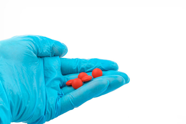 Käsineet punaisilla pillereillä, Lääketieteellisen työntekijän käsi lääketieteellisissä käsineissä pillereiden hallussapito - Valokuva, kuva