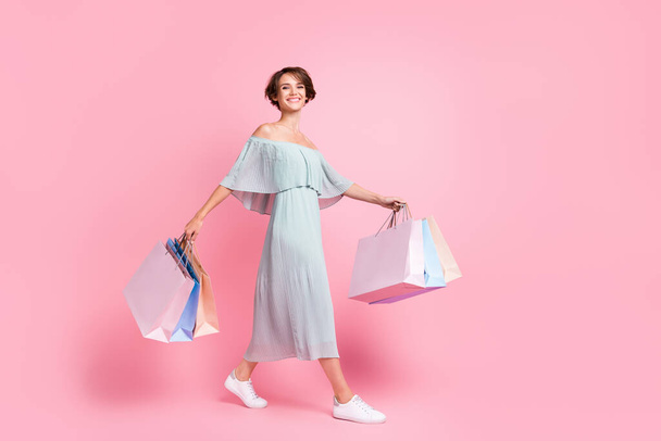 Full body profile side photo of young cheerful girl happy smile go walk hold shopping bags isolated over pastel color background. - Φωτογραφία, εικόνα