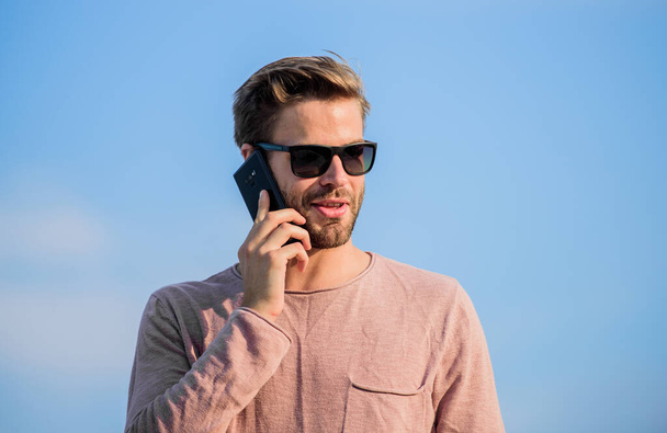 Application and internet. Hipster wear sunglasses hold mobile phone sky background. Hipster smartphone call. Important mobile conversation. Man mobile call. Stay in touch. Mobile call concept - Foto, imagen