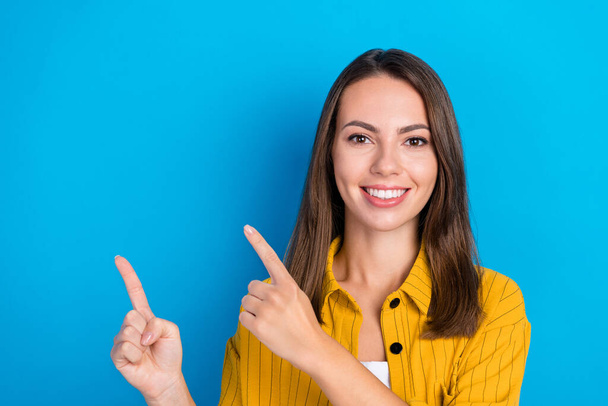 Photo of charming happy young woman point finger empty space comment follow news isolated on blue color background. - Фото, зображення