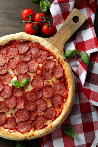 Concept of tasty food with Salami pizza on wooden background - Foto, imagen