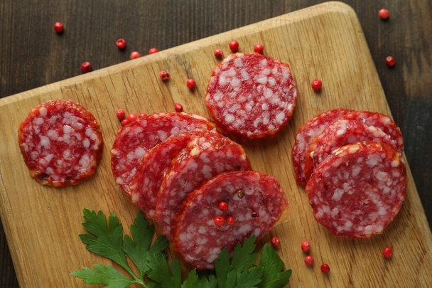 Concept van lekker eten met salami worst op donkere achtergrond - Foto, afbeelding