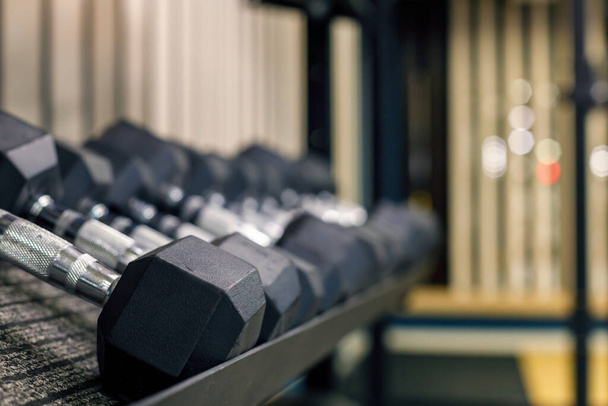 dumbbells are on a shelf in a row. gray large heavy dumbbells. sports equipment for the development of muscles - Photo, Image
