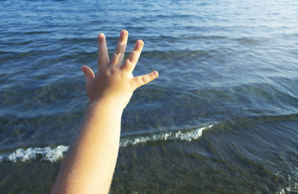 дитяча рука на фоні моря
 - Фото, зображення