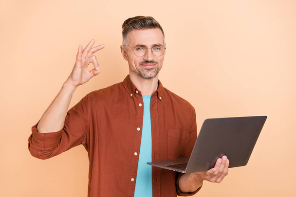 Photo of confident guy hold modern technology netbook show okey symbol great quarantine app using isolated over pastel color background. - Fotó, kép