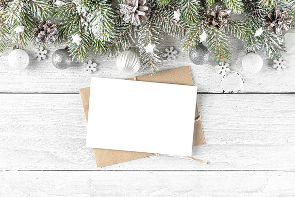 Christmas or Happy New Year greeting card with fir tree branches, holiday decorations on white wooden background. Flat lay. Mock up. Top view - Photo, Image