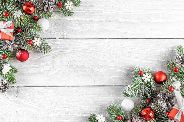 Navidad o Feliz Año Nuevo composición hecha de ramas de abeto, decoraciones de vacaciones rojas sobre fondo de madera blanca. Acostado. Vista superior con espacio de copia - Foto, imagen