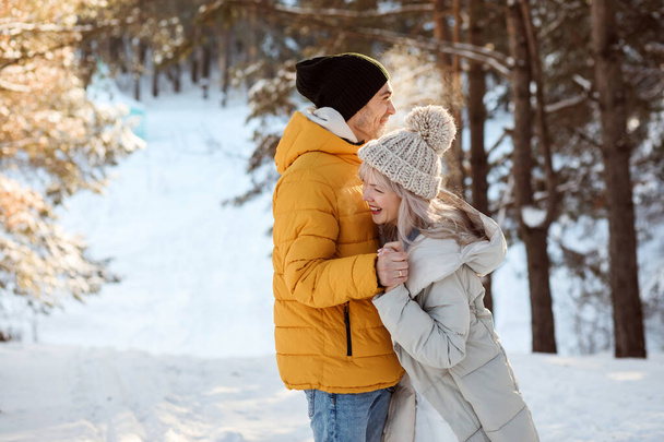Веселая пара веселится, смеется и улыбается в лесу на открытом воздухе зимой. - Фото, изображение