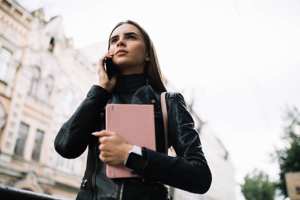 Millennial female student with education textbook using roaming internet connection for phone consultancy, Caucaisan tourist 20s making international conversation via smartphone application - Fotó, kép