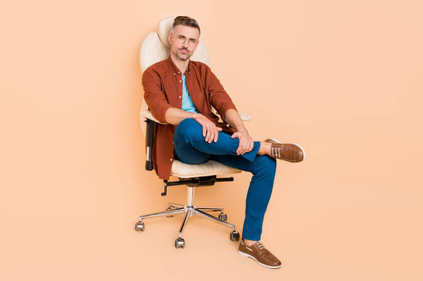 Full size photo of smart banker economist guy sit leather chair have partnership conference isolated over beige color background. - Photo, image
