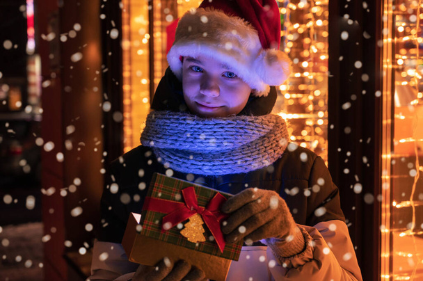 Niño en sombrero de Santas con caja de regalos mirando y soñando - Foto, Imagen