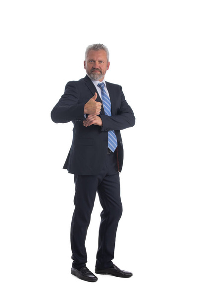 Full length portrait of smiling senior business man giving thumb up and holding a hand into suit pocket isolated on white background - Fotó, kép
