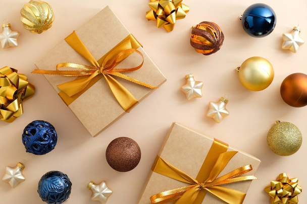 Christmas gifts with colorful ornaments on pastel beige background. Flat lay, top view. - 写真・画像