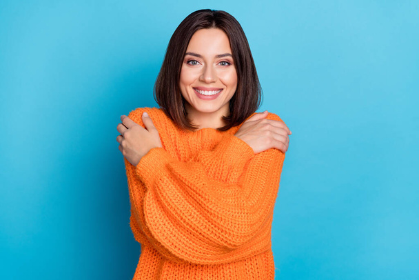 Portrait of attractive cheerful girl hugging herself wool clothes wear isolated over vivid blue color background. - Foto, afbeelding