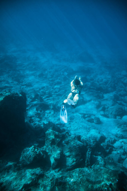 Podvodní střelecká dívka se potápí pod vodou the black swimsuit in clear water - Fotografie, Obrázek