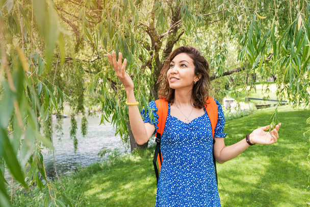 A woman walks in an idyllic willow forest on the bank of a small river. Relaxing outdoor recreation and the smell of woods - Photo, Image