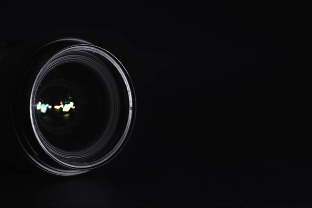 Optik der Kamera auf dem Bedienpult. Fackeln im Glas einer Fotolinse. Schwarzer Hintergrund mit der Technik des Fotografen.  - Foto, Bild