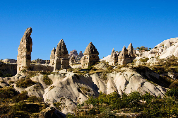 Amazing landscape view of ancient cave houses in Goreme at sunny autumn morning. Underground city inside the rocks. Fabulous landscapes of the mountains and spectacular rocks formations of Cappadocia. - Foto, afbeelding
