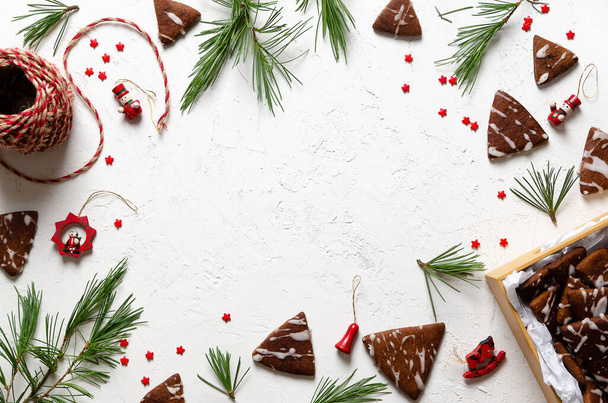 Pine branches, Christmas toys, little red stars, and chocolate cookies in a box and spread on a white background. - Foto, immagini
