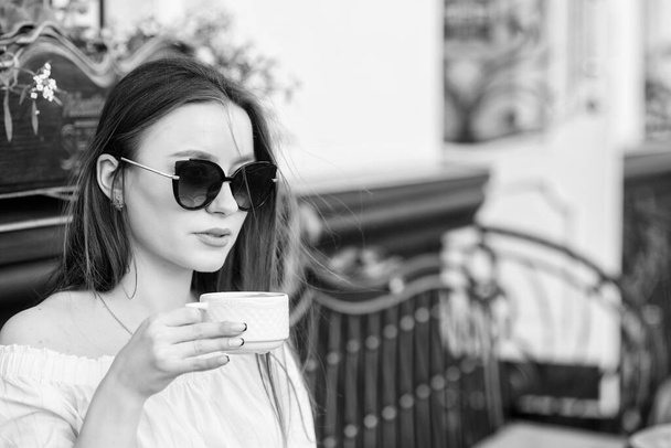 Girl relax in cafe cappuccino cup. Caffeine dose. Coffee for energetic successful day. Waiting for date. Breakfast time in cafe. Girl enjoy morning coffee. Woman in sunglasses drink coffee outdoors - Foto, Imagem