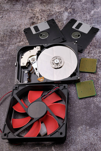 Composition of various computer components on a dark background similar to cement, different computer components such as hard drives, disk drives, graphic controller, micro chips, fans and heat sinks. - Photo, Image