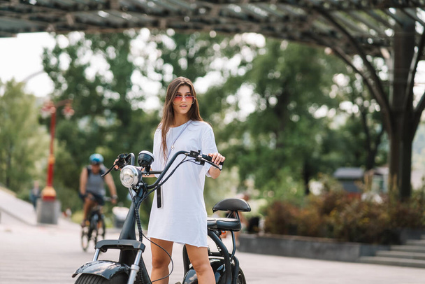 Молода красива жінка і електричний скутер, екологічний транспорт
 - Фото, зображення