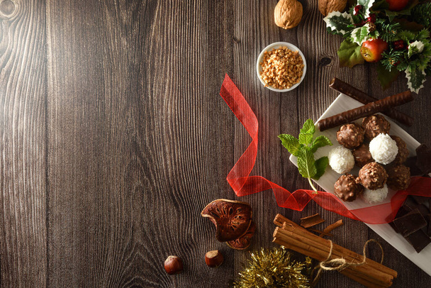Christmas table background with chocolate and coconut balls on wooden table with ingredients and nuts. Top view. - Photo, image