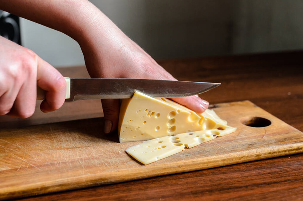 Slicing cheese on a wooden board. - Valokuva, kuva