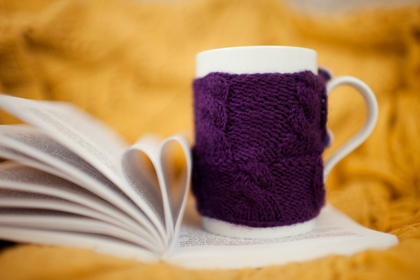 Knitted cup staying on open book - Photo, Image