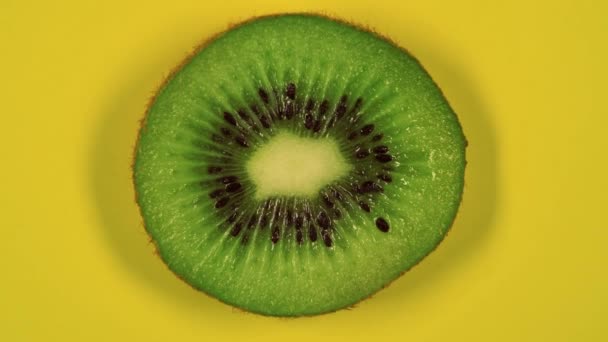 kiwi fetta girevole vista dall'alto su sfondo giallo.Macro food.Looped rotazione. Sano concetto di mangiare.Cibo biologico, cibo bio.. - Filmati, video