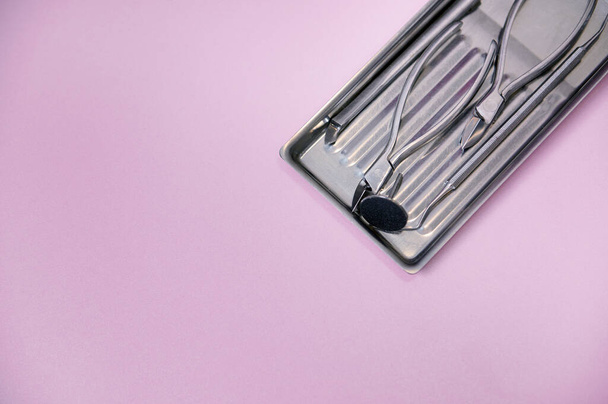 Close-up of a set of sterile stainless steel instruments for professional pedicure on colored background with copy space. Chiropody tools. - Valokuva, kuva