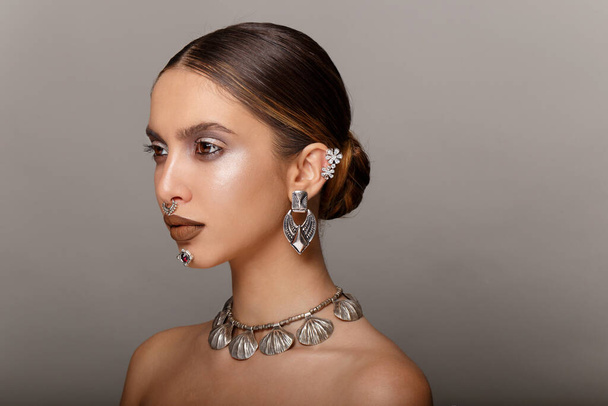 Horizontal view. Fashion pretty girl beauty portrait. Young woman with jewelry, hair arranged, makeup, looks to the side, with bare shoulders. Copy space. - Photo, Image