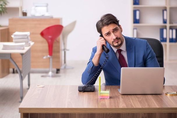 Jeune employé masculin assis sur le lieu de travail - Photo, image