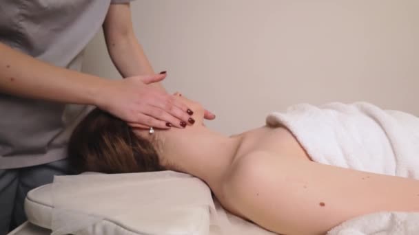 Woman masseur therapist kneading healthy head face massage relaxing professional therapy hands oil. Girl lying couch table resting gets rubdown spa salon body care concept, slow motion treatment - Footage, Video