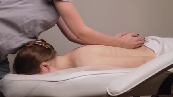 Mujer masajista terapeuta amasando saludable masaje de espalda relajante profesional terapia manos aceite. Chica tumbada mesa de centro de descanso se frota en el concepto de cuidado corporal salón de spa, tratamiento de cámara lenta - Imágenes, Vídeo