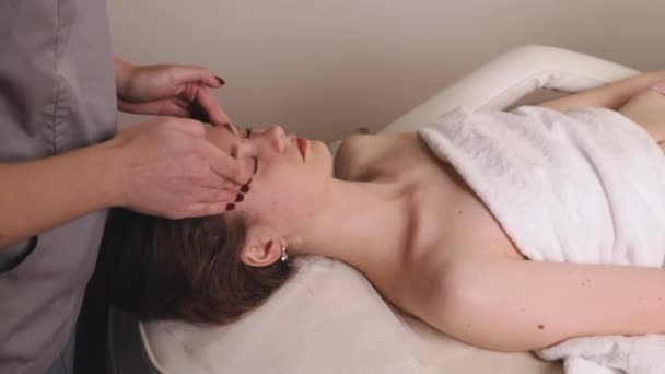 Mujer masajista terapeuta amasar la cabeza sana masaje facial relajante terapia profesional manos aceite. Chica tumbada mesa de centro de descanso se frota concepto de cuidado corporal salón de spa, tratamiento de cámara lenta - Metraje, vídeo