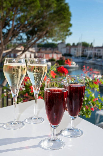 Zomer feest met kir koninklijke cocktail, proeverij van Franse brut champagne mousserende wijn en koude crème cassis in glazen in jachthaven van Port Grimaud in de buurt van Saint-Tropez, Côte d 'Azur vakantie, Frankrijk - Foto, afbeelding