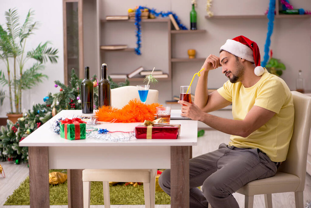 Młody mężczyzna sprząta mieszkanie po przyjęciu świątecznym - Zdjęcie, obraz