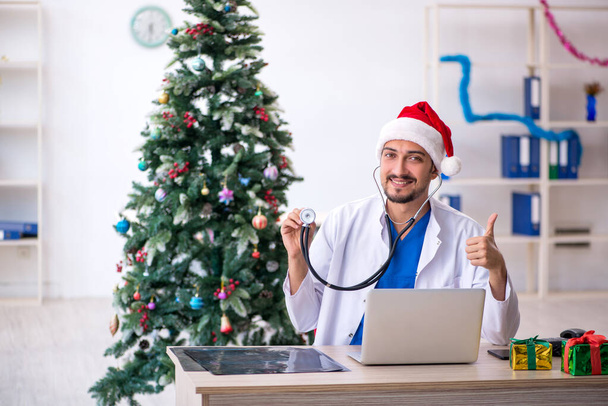 Genç erkek doktor Noel 'i hastanede kutluyor. - Fotoğraf, Görsel