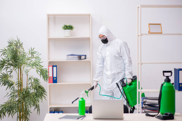 Young male contractor disinfecting office during pandemic - Foto, Bild