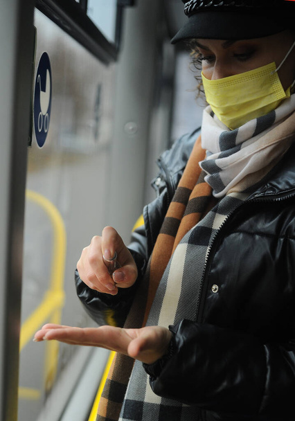 mujer en una máscara protectora en el autobús, la observación de medidas de cuarentena desinfecta sus manos - Foto, Imagen