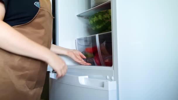 Nainen ottaa tuoretta paprikaa jääkaapista. Ruoanlaitto terveellistä ruokaa kotona keittiössä. Ympäristöystävällinen elämäntapa. - Materiaali, video