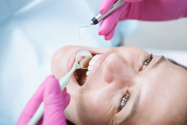 Περικοπή κοντά σε μια γυναίκα ασθενή για τον έλεγχο των δοντιών από τον οδοντίατρο - Φωτογραφία, εικόνα