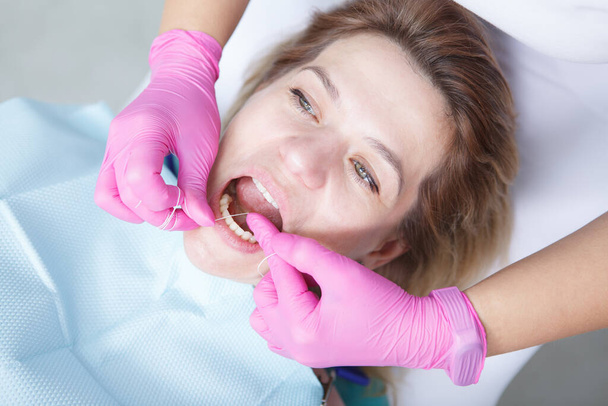 Vue de dessus gros plan d'une femme mature ayant ses dents en soie dentaire par un dentiste professionnel - Photo, image