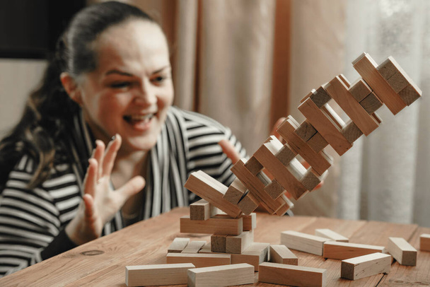 Mom and daughter play a board game, build a tower from wooden blocks. - Fotó, kép