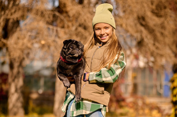Pretty blonde girl holding her dog and smiling - Foto, Imagem